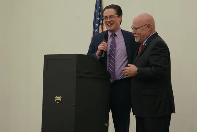 Ken Massey shares a laugh with a fellow speaker at the podium